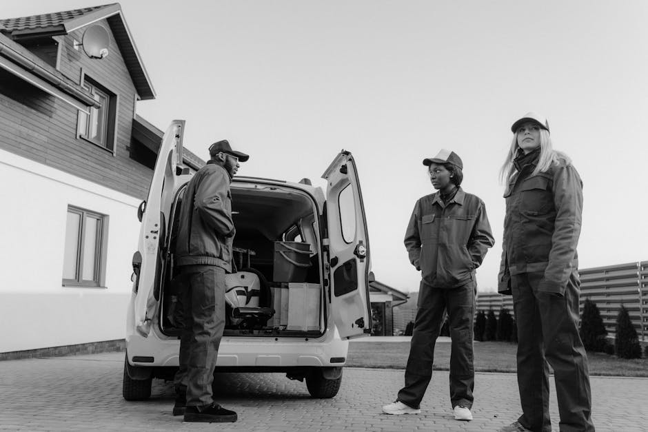 Three workers in coveralls unload equipment from a van, showcasing teamwork and diversity.